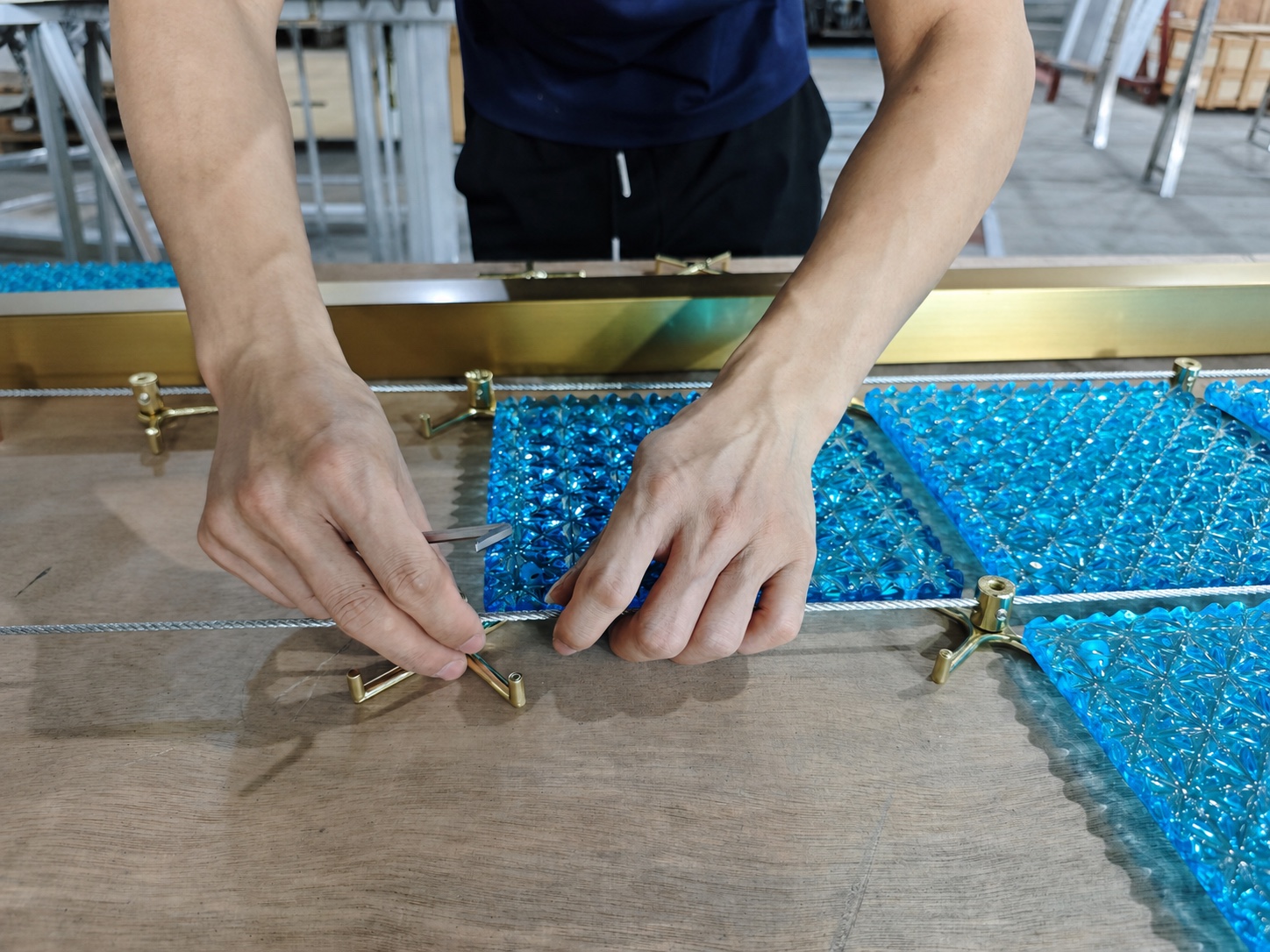 Hands positioning a metal connector between blue crystal modules