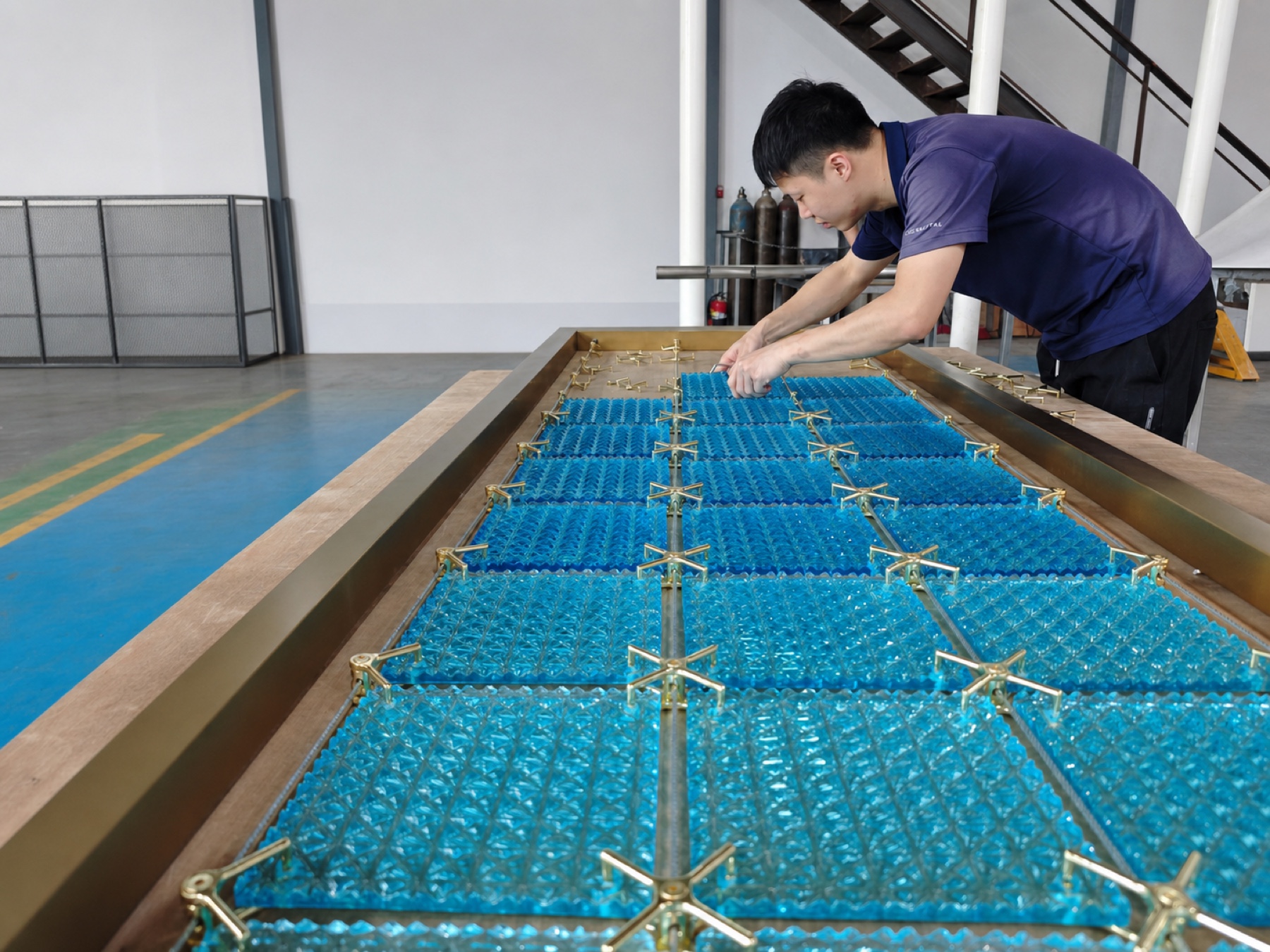 Workshop technician positioning blue crystal modules and metal connectors inside a gold frame